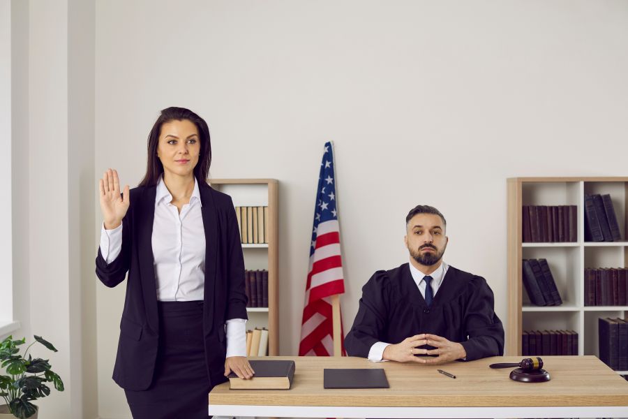 Female witness swears before testifying that she will tell truth and nothing but truth. Woman takes oath before testifying in court. Concept of litigation, law, decision and justice.