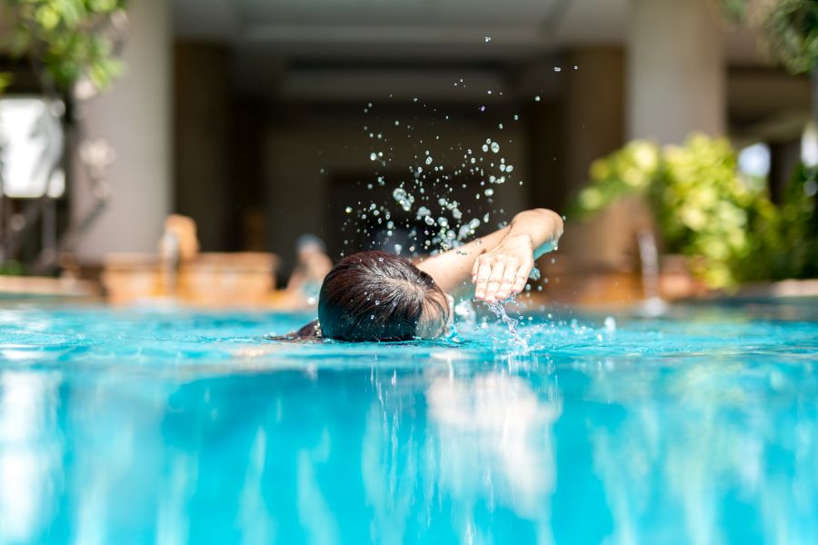 Unidentified woman doing front crawl swimming in swimming pool on vacation