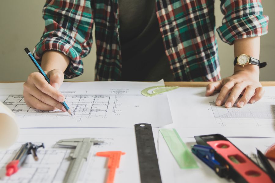 Concept architects,woman engineer holding pen pointing equipment architects On the desk with a blueprint in the office, Vintage, Sunset light.Selective Focus