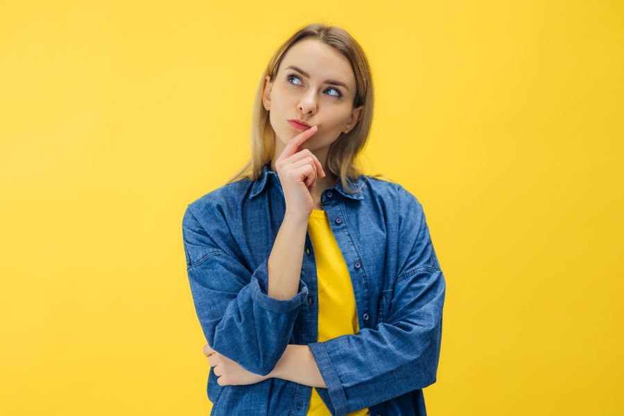 Pensive suspicious attractive woman looking for answers on her questions isolated on yellow background